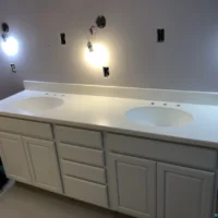 a bathroom with white counter tops and lights